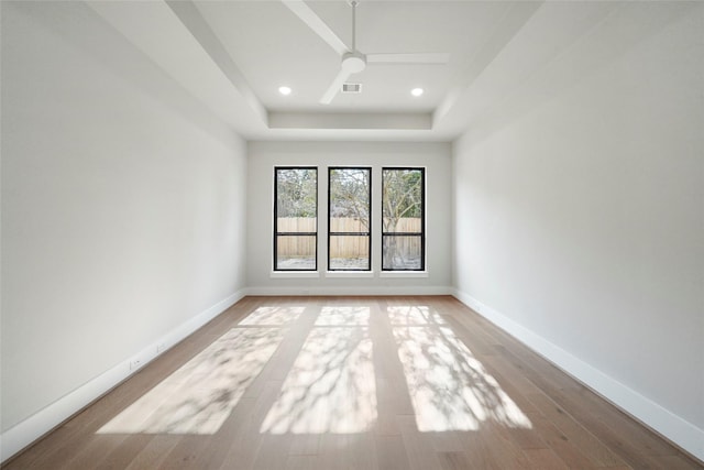 unfurnished room featuring wood finished floors, ceiling fan, a tray ceiling, baseboards, and recessed lighting