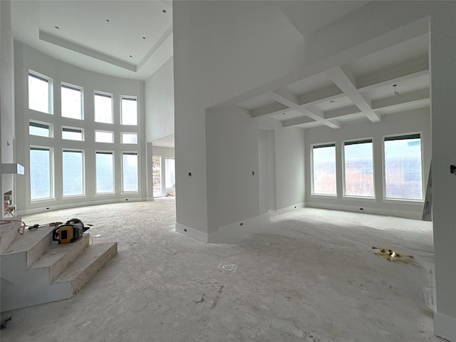 unfurnished living room with coffered ceiling, beamed ceiling, and a high ceiling