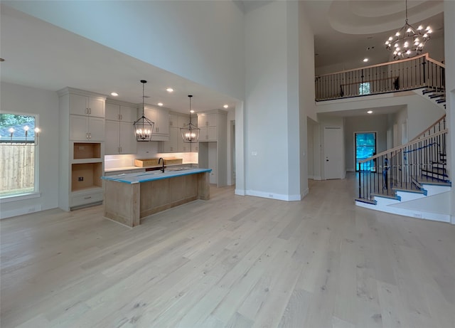 kitchen with light wood-style floors, a high ceiling, and an inviting chandelier