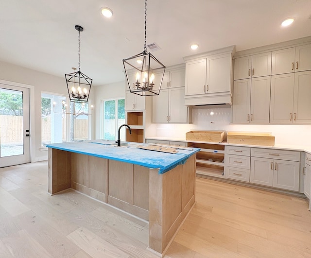 9607 Kerrwood Ln, Houston, TX 77080 - kitchen with a chandelier, light wood-type flooring, a sink, a kitchen island with sink, and recessed lighting