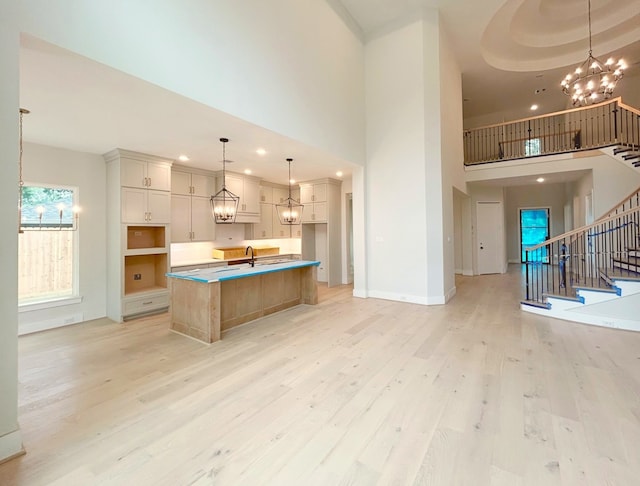 9607 Kerrwood Ln, Houston, TX 77080 - kitchen featuring a chandelier, light wood-style flooring, a high ceiling, baseboards, and an island with sink