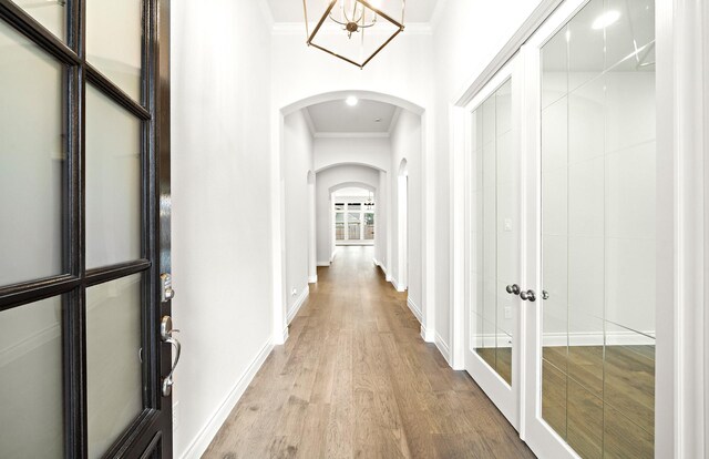 hall with ornamental molding, french doors, and light wood-type flooring