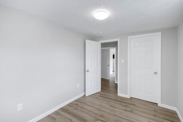 unfurnished bedroom featuring light wood-type flooring and a textured ceiling