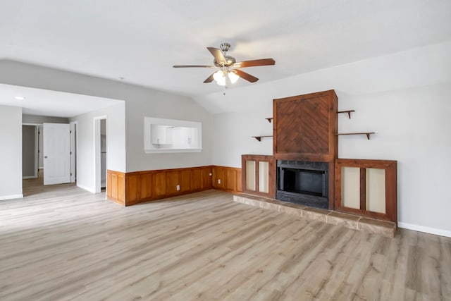 unfurnished living room featuring a large fireplace, light hardwood / wood-style floors, ceiling fan, and vaulted ceiling