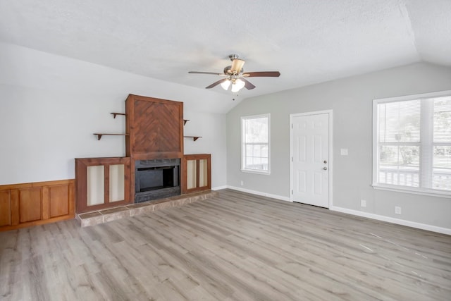 unfurnished living room with a textured ceiling, light hardwood / wood-style flooring, ceiling fan, and vaulted ceiling