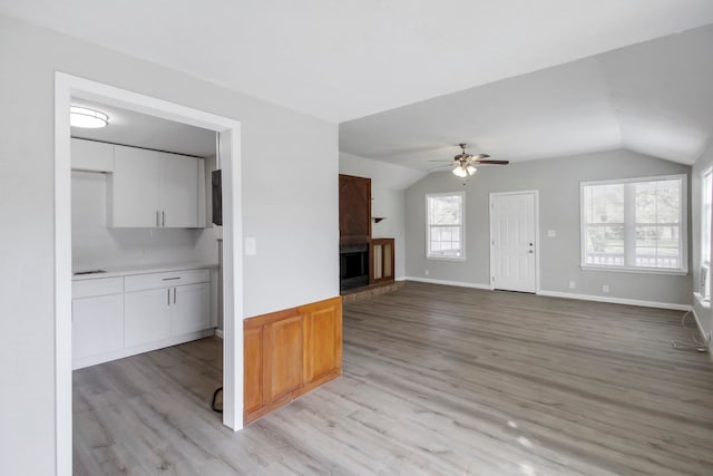 unfurnished living room with light hardwood / wood-style flooring, lofted ceiling, and ceiling fan