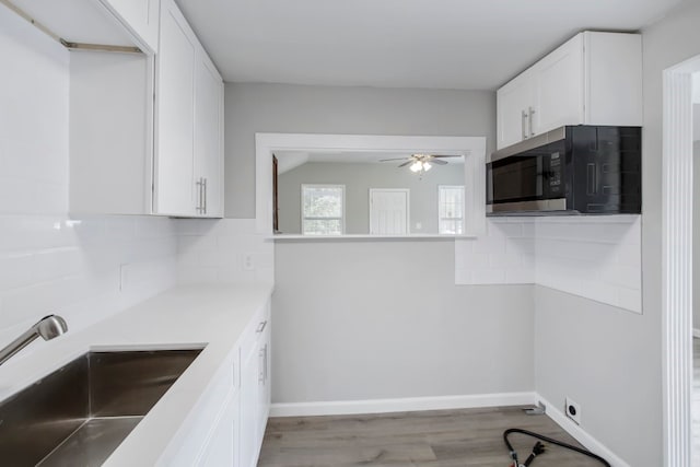 kitchen with white cabinets, light hardwood / wood-style floors, sink, and backsplash