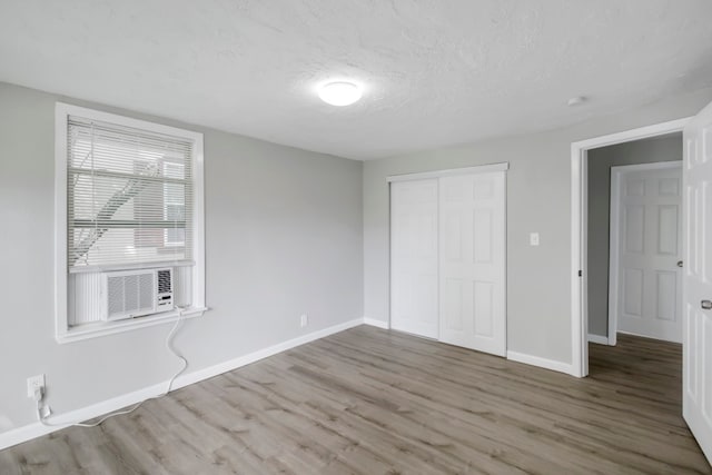 unfurnished bedroom featuring wood-type flooring, cooling unit, and a closet