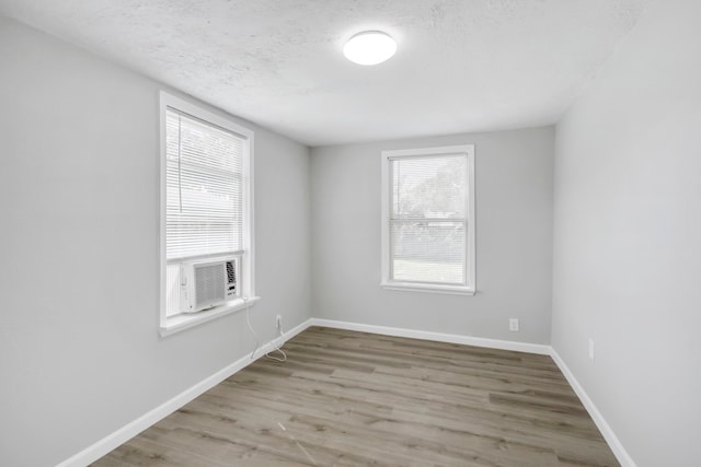 spare room with cooling unit, a textured ceiling, and light hardwood / wood-style flooring