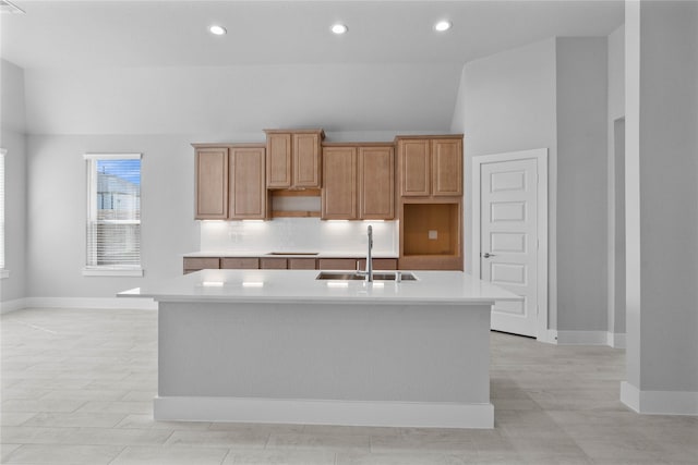 kitchen featuring a center island with sink, backsplash, sink, and vaulted ceiling