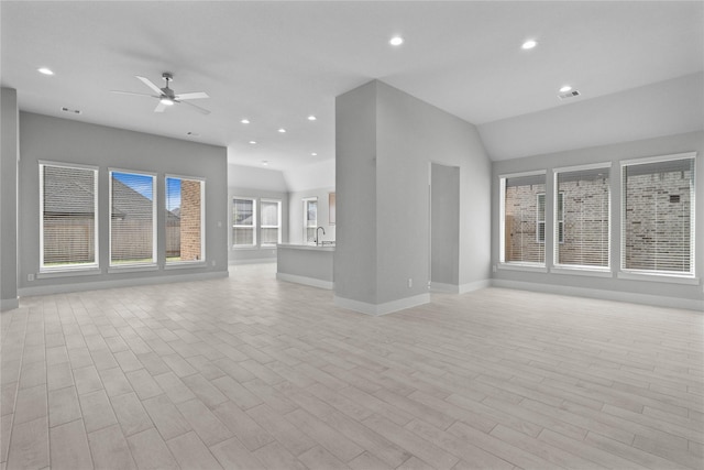 unfurnished living room with ceiling fan and vaulted ceiling