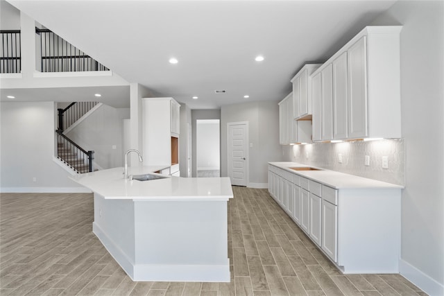 kitchen featuring tasteful backsplash, white cabinetry, sink, and light hardwood / wood-style floors