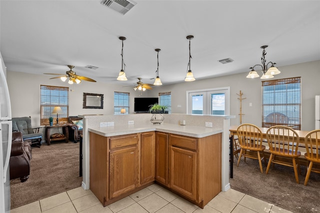 kitchen featuring a center island, decorative light fixtures, light carpet, and ceiling fan with notable chandelier