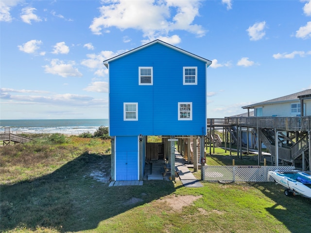 rear view of property with a water view, a beach view, and a yard