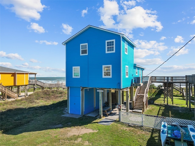 back of house with central AC unit, a yard, and a deck with water view