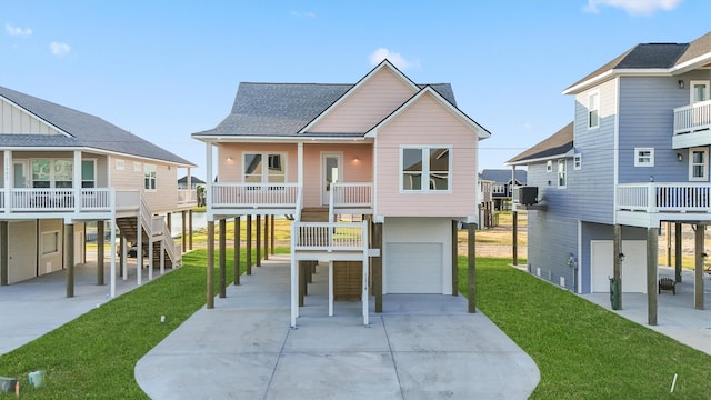 beach home featuring a garage, a front yard, a porch, and central AC