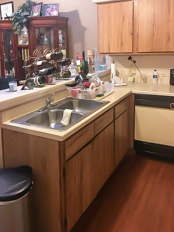 kitchen featuring dishwasher, dark hardwood / wood-style flooring, kitchen peninsula, and sink