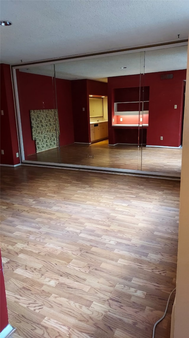 unfurnished room with wood-type flooring and a textured ceiling