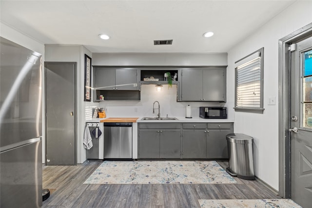 kitchen featuring dark hardwood / wood-style flooring, gray cabinetry, appliances with stainless steel finishes, and sink