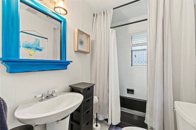 full bathroom with tasteful backsplash, tile walls, shower / bath combination with curtain, sink, and toilet