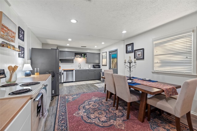 dining area featuring a wealth of natural light, a textured ceiling, sink, and dark hardwood / wood-style flooring