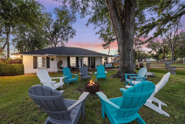 back house at dusk with a fire pit and a yard