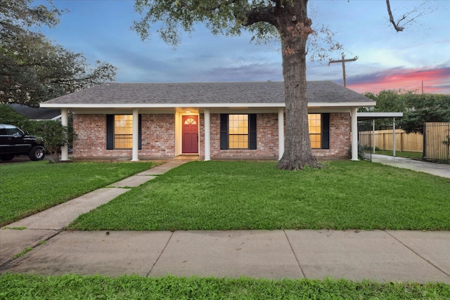 single story home with covered porch, a carport, and a lawn