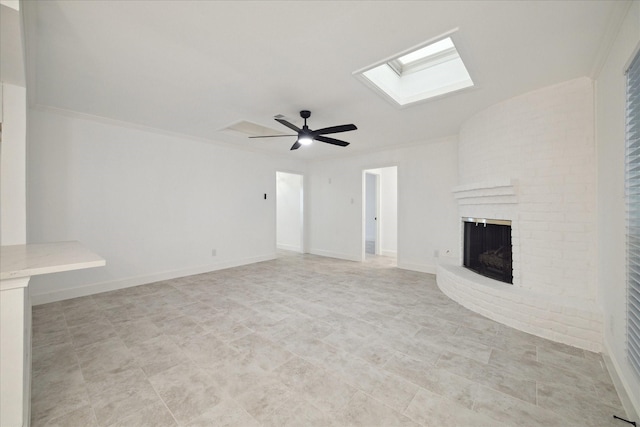 unfurnished living room featuring a skylight, a fireplace, ceiling fan, and ornamental molding