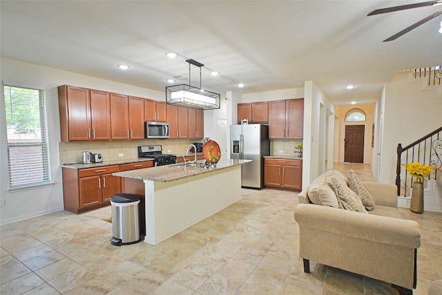 kitchen with tasteful backsplash, a center island with sink, stainless steel appliances, pendant lighting, and sink