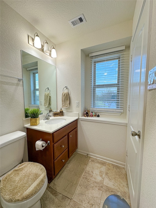 bathroom featuring vanity, a textured ceiling, and toilet