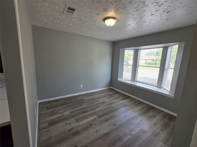 unfurnished room with dark wood-type flooring and a textured ceiling