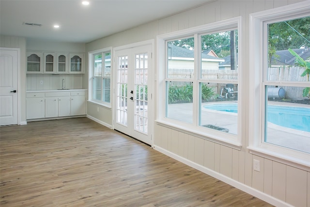 doorway to outside with light hardwood / wood-style floors, sink, a healthy amount of sunlight, and french doors