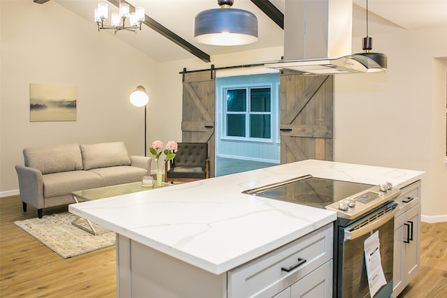 kitchen featuring a barn door, pendant lighting, stainless steel range with electric cooktop, and light hardwood / wood-style flooring