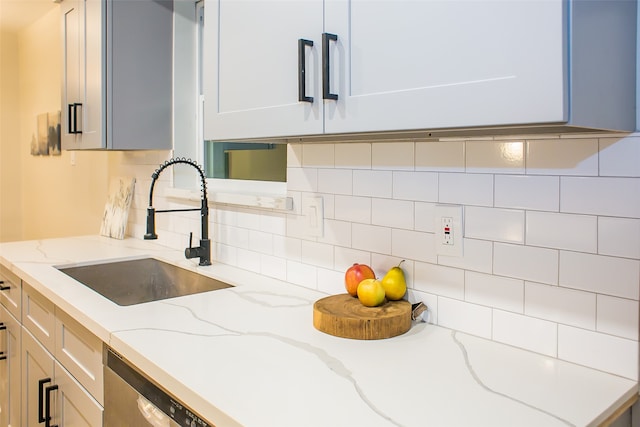 kitchen with light stone countertops, sink, backsplash, and dishwasher