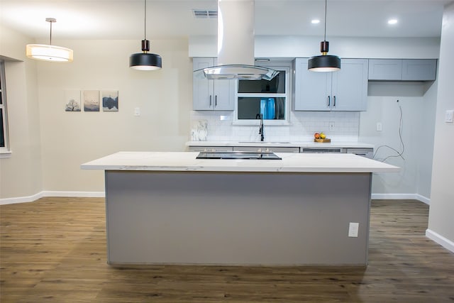 kitchen with tasteful backsplash, light stone countertops, island range hood, decorative light fixtures, and dark wood-type flooring