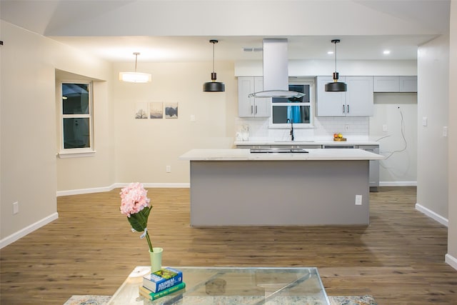 kitchen with pendant lighting, sink, decorative backsplash, hardwood / wood-style floors, and a center island