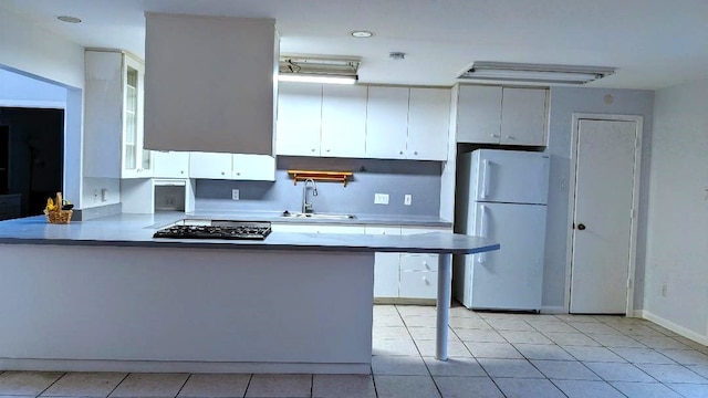 kitchen featuring stainless steel gas stovetop, white refrigerator, white cabinets, kitchen peninsula, and sink