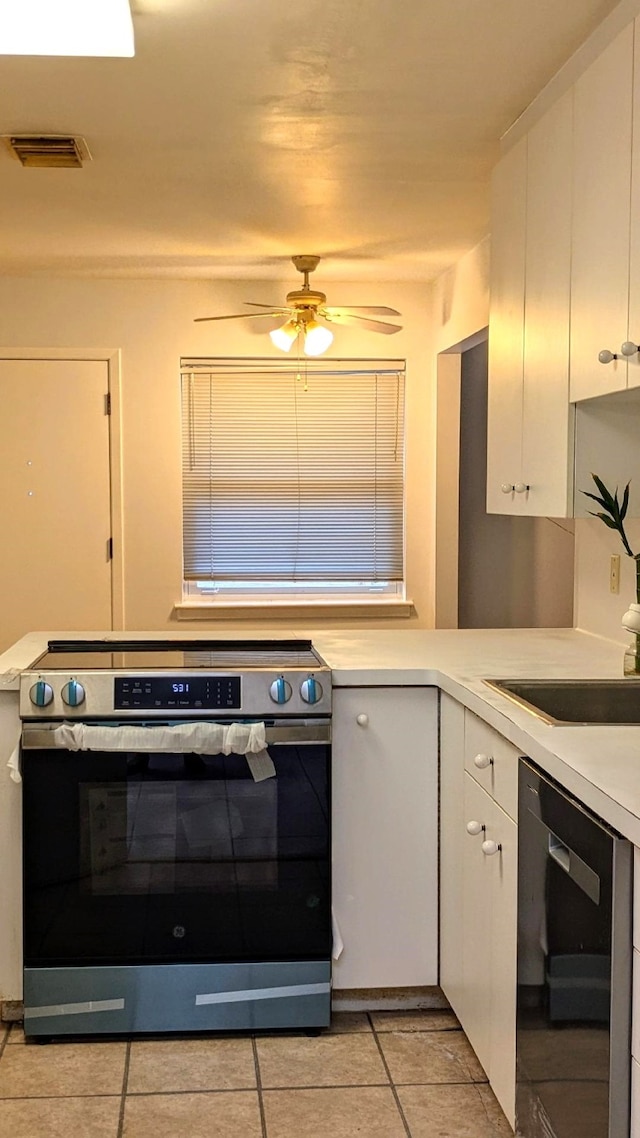 kitchen with black dishwasher, white cabinets, light tile patterned floors, ceiling fan, and electric range