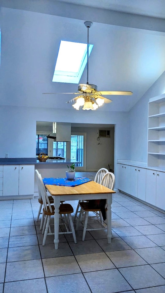 tiled dining space with ceiling fan and vaulted ceiling with skylight