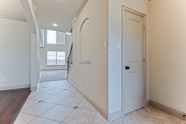 hallway with light tile patterned flooring and crown molding