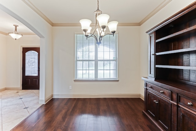 entrance foyer with ornamental molding, dark wood-type flooring, and a chandelier