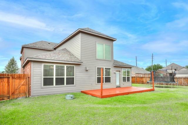 rear view of property featuring a patio, a yard, and a trampoline