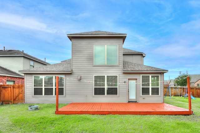 back of property with a deck, a lawn, and a playground