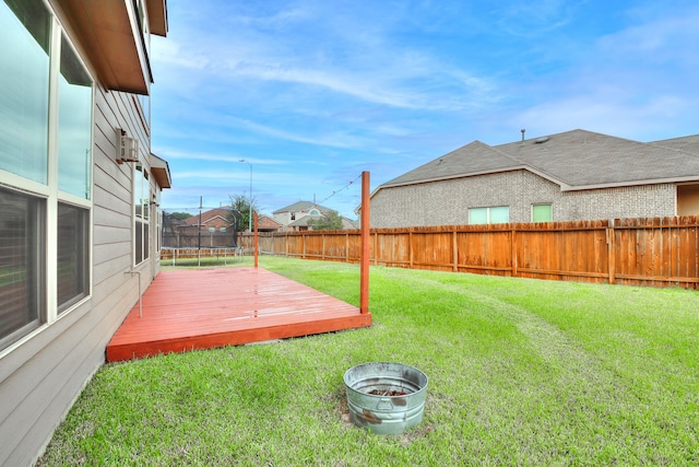 view of yard with a trampoline and a deck