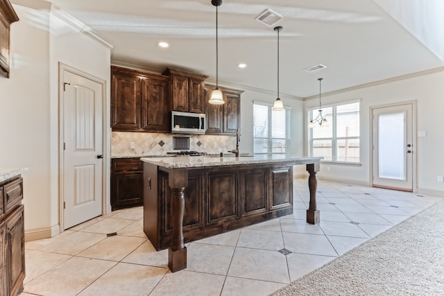 kitchen with a center island with sink, light stone counters, light tile patterned floors, a breakfast bar, and pendant lighting