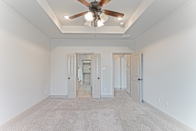 unfurnished bedroom with light colored carpet, ceiling fan, and a tray ceiling