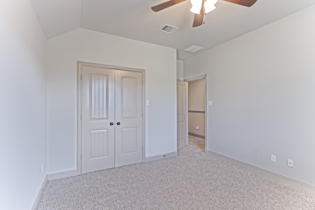 unfurnished bedroom featuring light colored carpet, ceiling fan, vaulted ceiling, and a closet