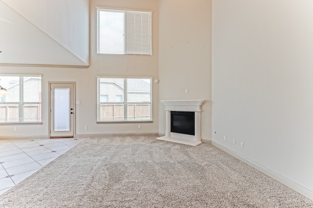 unfurnished living room with light colored carpet, a healthy amount of sunlight, and a high ceiling