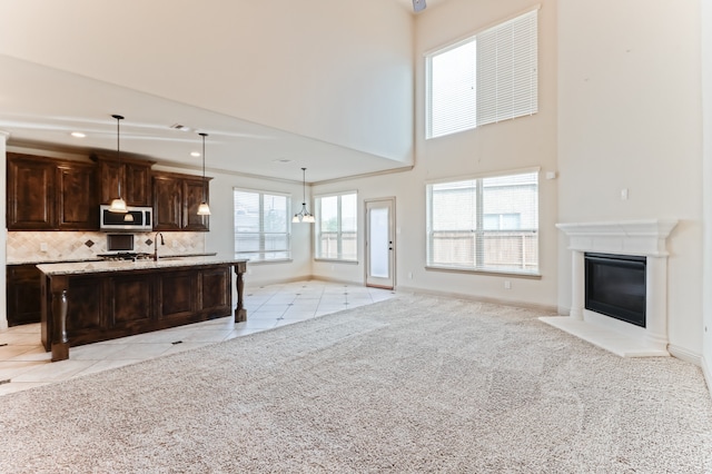 kitchen featuring hanging light fixtures, plenty of natural light, light carpet, and a kitchen island with sink