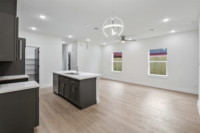 kitchen featuring dishwasher, hanging light fixtures, an island with sink, light hardwood / wood-style floors, and ceiling fan with notable chandelier